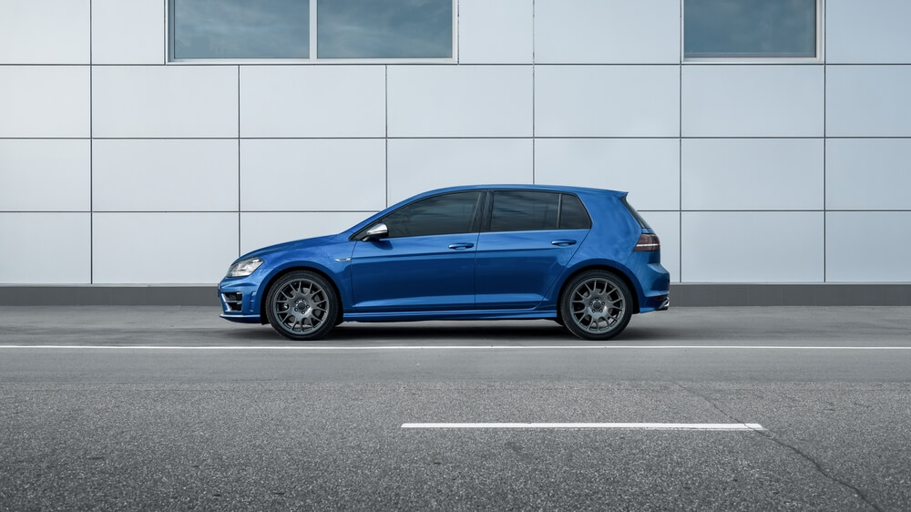 Volkswagen Golf R in front of the gray wall. Side profile view.